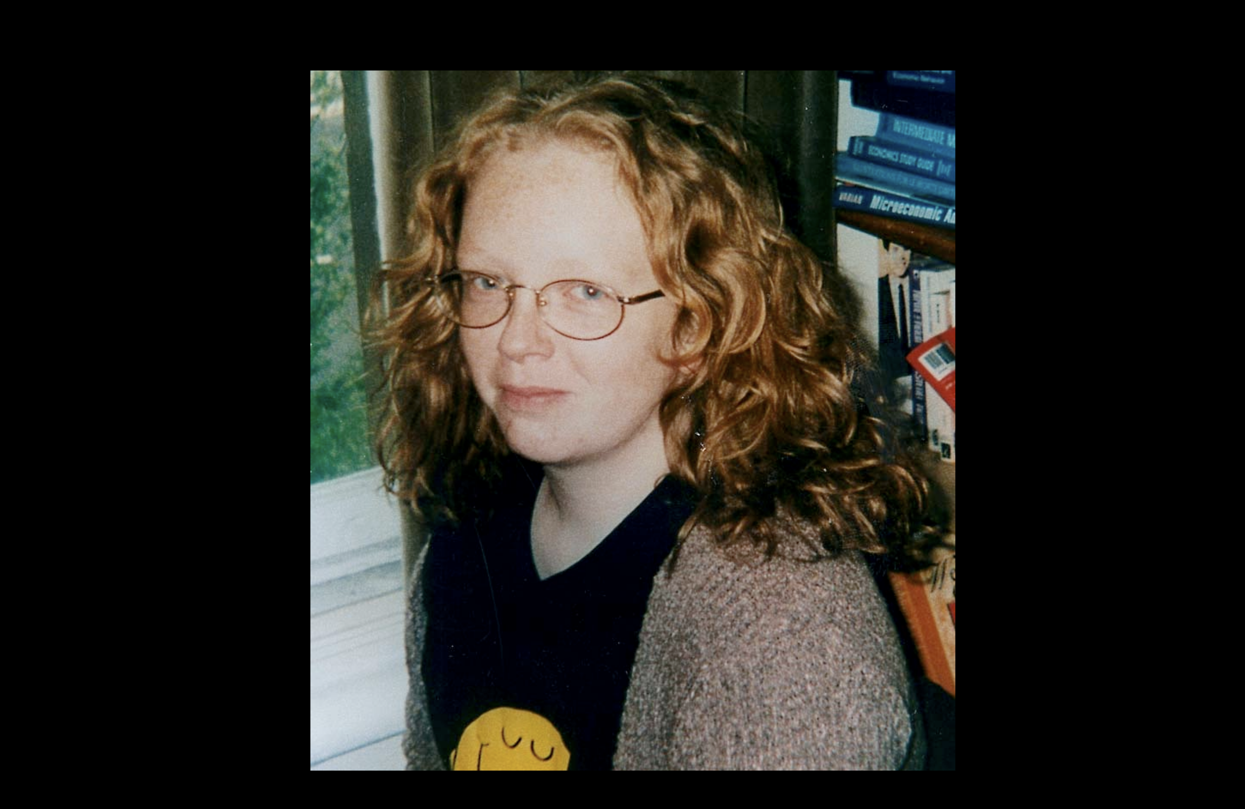 An extremely non-dorky picture of me in front of economics textbooks. I'm wearing a Mr Happy tshirt