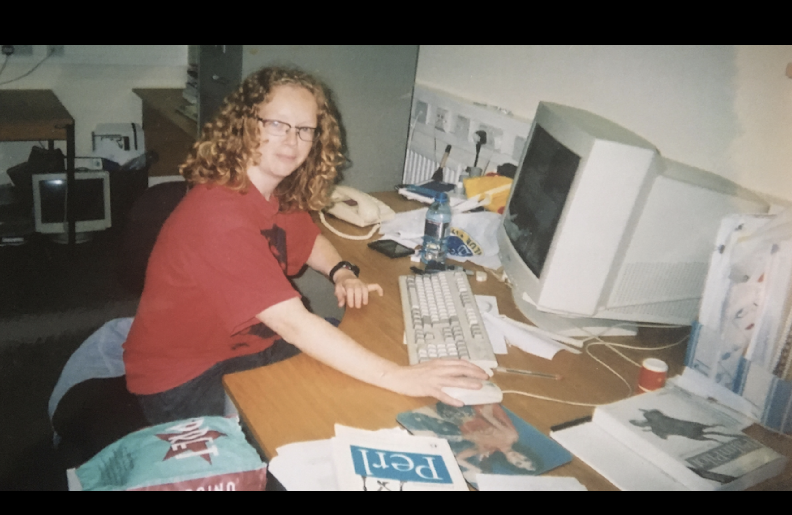 An extremely dorky-looking picture of me with my hand on a mouse and with an old-fashioned beige CRT monitor and surrounded by Oreilley books e.g. on Perl and Palmpilot