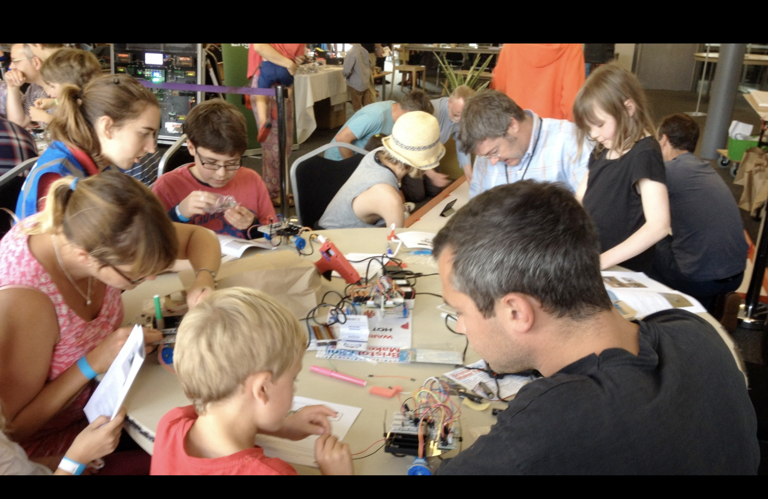 A group of children and adults sitting round a table intent on making shonkbots