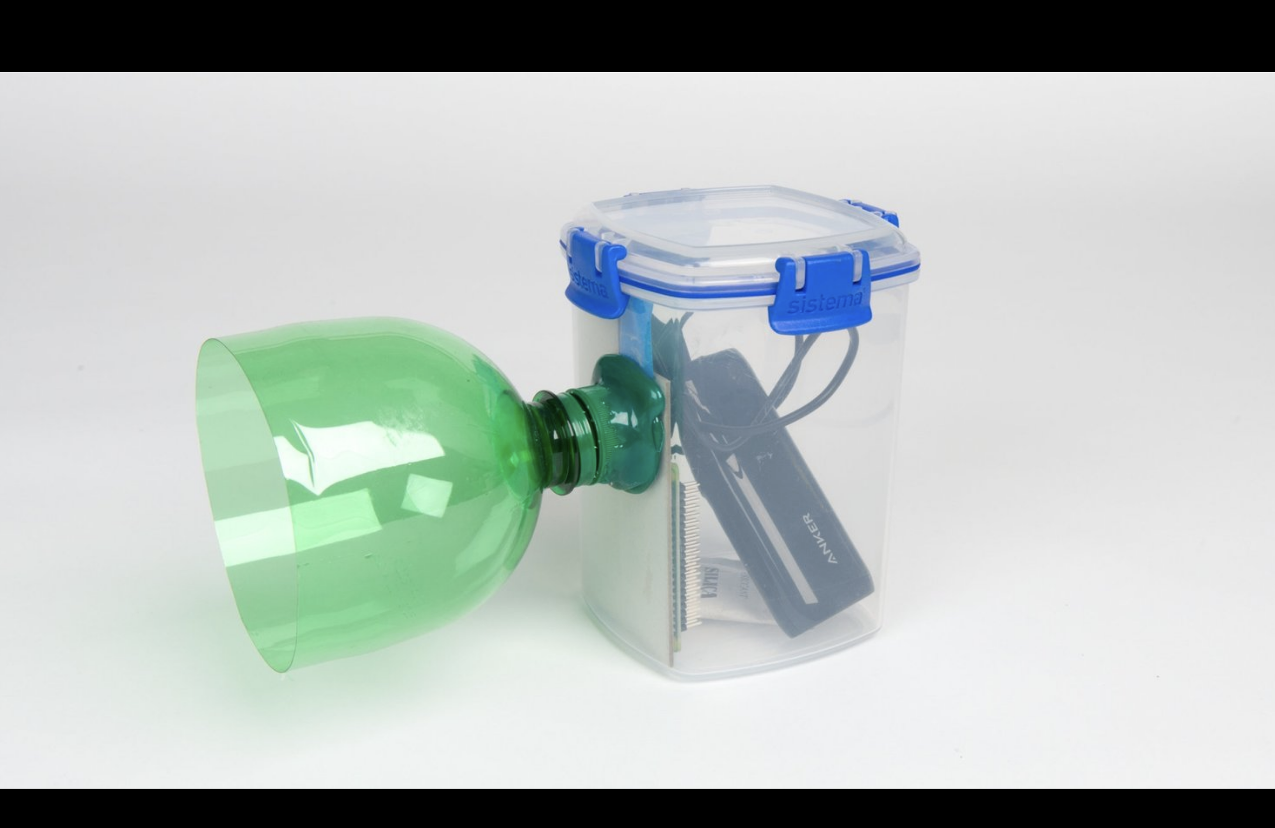 A home made nature camera consisting of a sandwich box with a raspberry pi and a battery in it and the top of a lemonade bottle glued to the side to protect the camera.