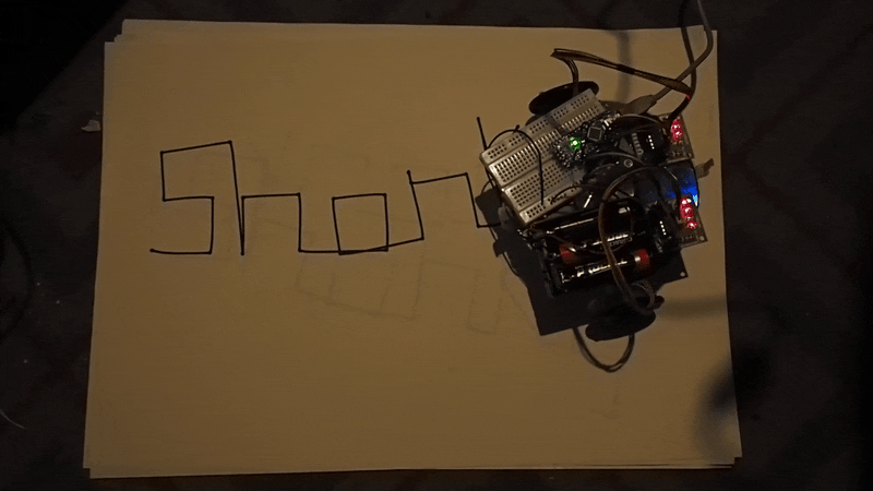 An animated gif showing a shonkbot writing its name, viewed from above.