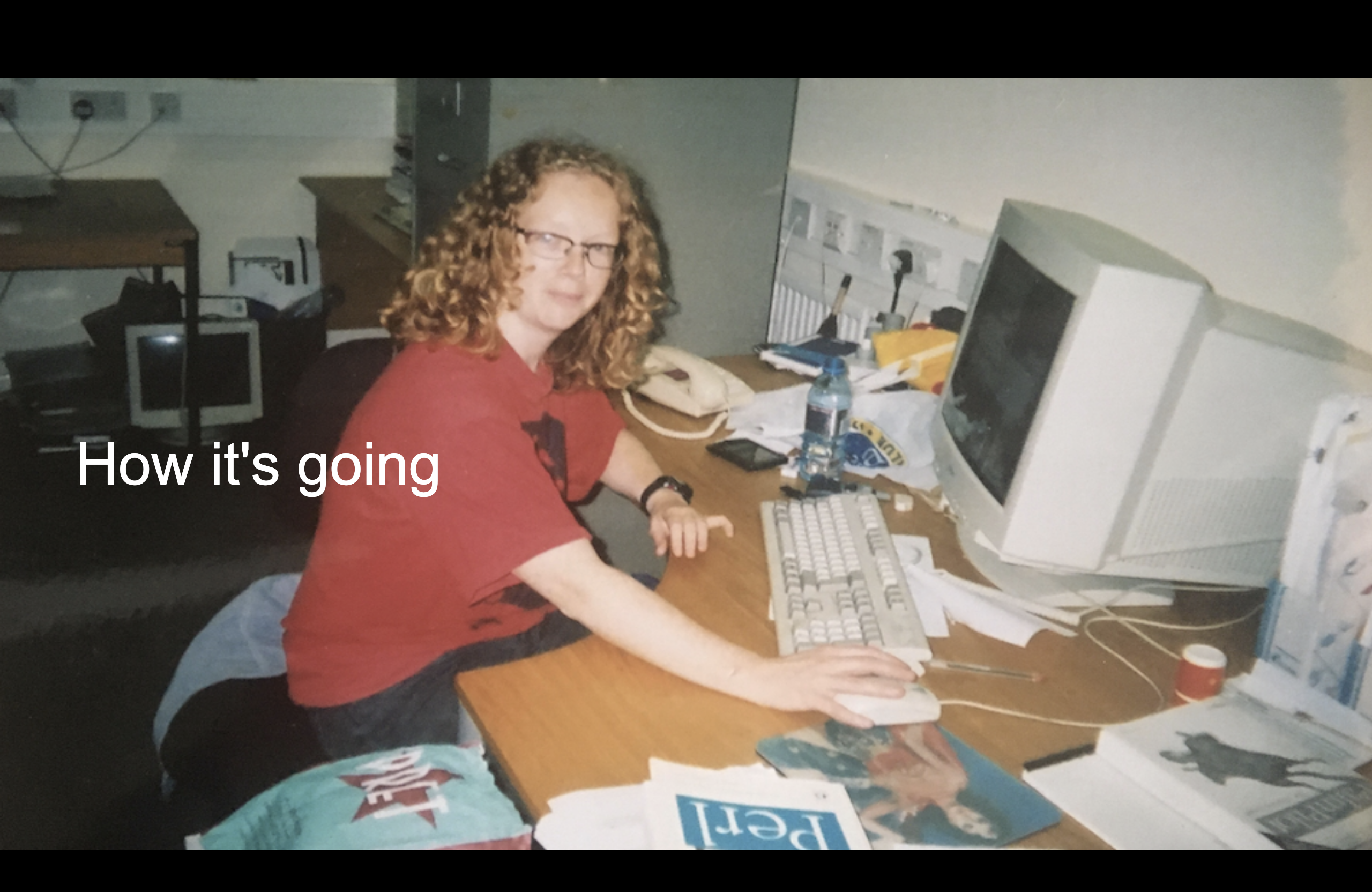 A very geeky looking Libby in front of an old CRT monitor surrounded by computer books entitled how it's going